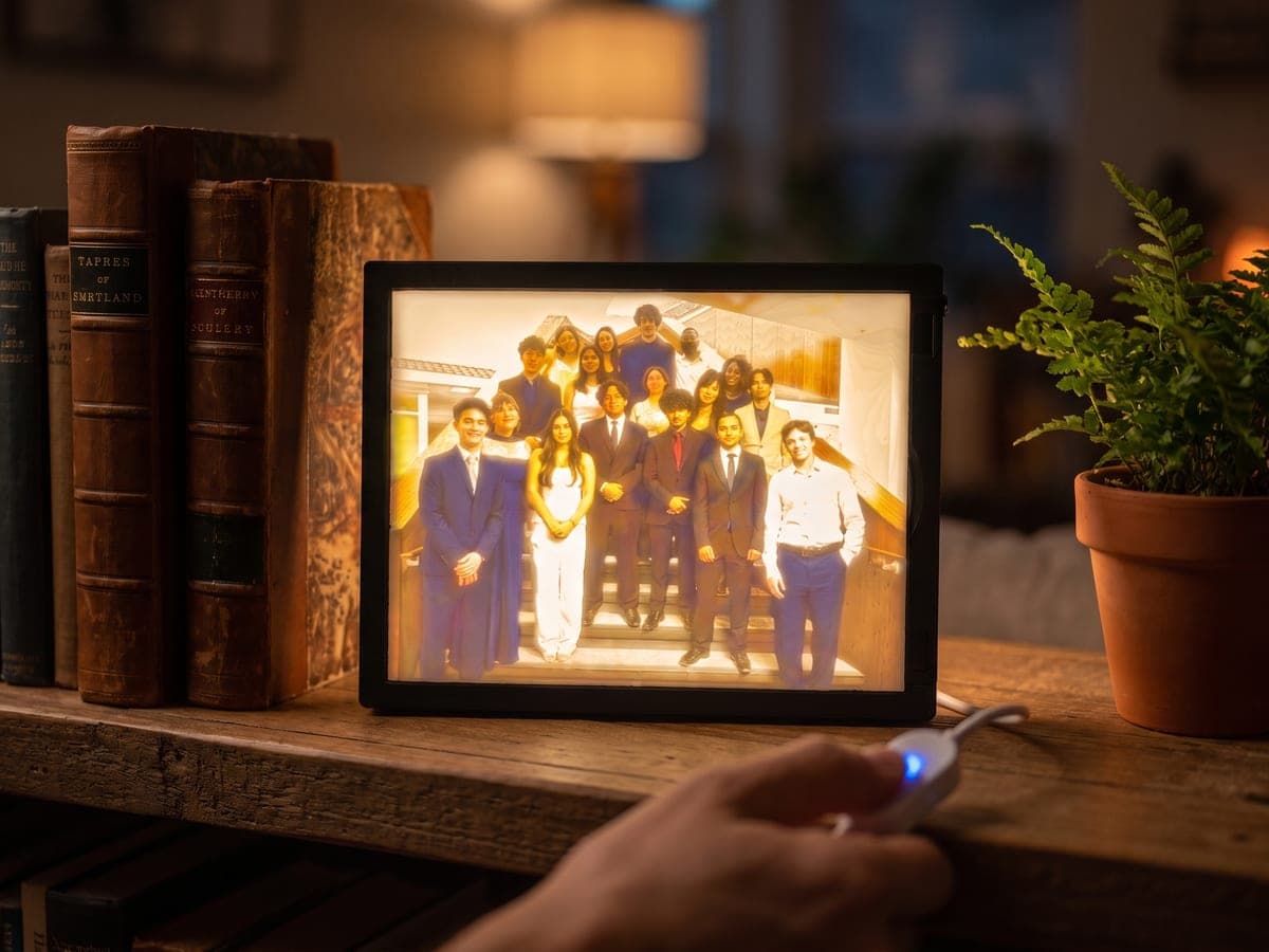 A hand pressing the small switch as a framed lithophane lights up on a shelf