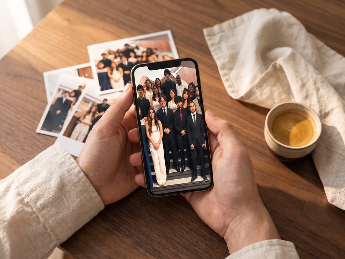 Hands holding a phone showing a group photo of friends, ready to upload